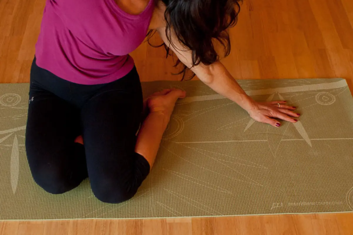 Close-up of a person kneeling on a Pilates mat during floor practice